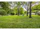 Large, well-manicured backyard with mature trees and a fire pit seating area at 11710 Prairie Pl, Carmel, IN 46033