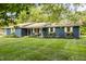 A cozy, single-story home with a blue brick facade, surrounded by a well-manicured lawn and mature trees at 11710 Prairie Pl, Carmel, IN 46033