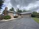 Quaint brick home featuring an attached garage, chimney and cracked asphalt driveway at 145 Goodnight Rd, Martinsville, IN 46151