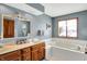 Well-lit bathroom with double sinks, bathtub, and a decorative mirror at 1852 Lakeside Ln, Indianapolis, IN 46229