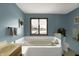 Bright bathroom with tub, blue walls, and natural light at 1852 Lakeside Ln, Indianapolis, IN 46229