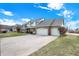 View of a two-story home with a brick and siding exterior, three-car garage, and a long driveway at 1852 Lakeside Ln, Indianapolis, IN 46229