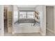 Bathroom featuring a tiled standalone tub, gray walls, and decorative geometric shelving at 20451 Chatham Hills Blvd, Westfield, IN 46074