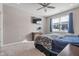 A serene bedroom is decorated with a ceiling fan, a large window, and an elegant blue comforter at 293 Carrick Glen Blvd, Pendleton, IN 46064