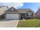 Charming single-story home featuring brick accents, gray siding, a two-car garage, and a well-manicured lawn at 293 Carrick Glen Blvd, Pendleton, IN 46064