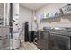 Well-equipped laundry room with grey washer and dryer, shelving, and utility equipment at 293 Carrick Glen Blvd, Pendleton, IN 46064