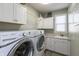 Bright laundry room with white cabinetry, modern washer and dryer, and a convenient sink area at 3982 Abbotsford Dr, Westfield, IN 46074