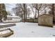 Large backyard featuring a storage shed, patio area, and a lawn covered in snow at 5937 Broadway St, Indianapolis, IN 46220