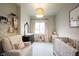 Well-lit Bedroom with a crib, rocking chair, black dresser, and soft patterned wallpaper at 6047 Guilford Ave, Indianapolis, IN 46220