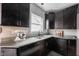 Kitchen featuring granite counters, stainless appliances, tiled backsplash, and dark wood cabinets at 6047 Guilford Ave, Indianapolis, IN 46220