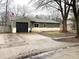 Well-maintained home with green siding, dark roof, and a paved driveway leading to an attached garage at 7824 Inverness Dr, Indianapolis, IN 46237