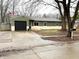 Charming single-story home featuring a black garage door, neat landscaping, and an inviting front entrance at 7824 Inverness Dr, Indianapolis, IN 46237