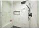 Modern shower featuring marble-look tile, a built-in niche, rainfall shower head, and sleek black hardware at 8545 Olde Ml Trce, Indianapolis, IN 46260