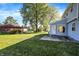 A spacious, grassy backyard with mature trees and landscaping and a side view of the sunroom at 908 Whispering Trl, Greenfield, IN 46140