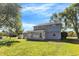 Large backyard showcasing the home's sunroom, mature trees, and ample green space for recreation at 908 Whispering Trl, Greenfield, IN 46140