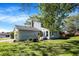 Well-maintained backyard with lush green grass, mature trees, and comfortable seating near the sunroom at 908 Whispering Trl, Greenfield, IN 46140