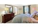 Bedroom with wood dresser, mirror, a view of the bathroom, and a window with patterned curtains at 908 Whispering Trl, Greenfield, IN 46140