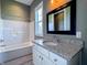 This bathroom has a tub/shower combo and a granite countertop vanity with a black framed mirror at 10297 Anees Ln, Fishers, IN 46040