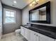 Bathroom with granite countertop, white cabinets, black framed mirror, and natural light from a window at 10297 Anees Ln, Fishers, IN 46040