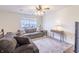 A living room features two sofas, a ceiling fan, and natural light from a large window at 11005 Long Lake Ln, Fishers, IN 46037