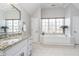 Bright bathroom with a soaking tub, granite counters, white cabinetry, and large windows overlooking nature at 11727 Windpointe Pass, Carmel, IN 46033