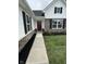 Inviting front entrance with a red door, stone accents, black shutters, and well-kept landscaping at 1202 Brightwood Cir, Greenfield, IN 46140
