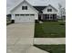 Charming two-story home featuring a two-car garage, a red door, and a well-manicured lawn at 1202 Brightwood Cir, Greenfield, IN 46140