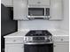 Close-up of a kitchen stove with stainless steel appliances, white quartz countertops, and light gray cabinets at 1202 Brightwood Cir, Greenfield, IN 46140