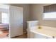 View from bedroom through door to an inviting bathroom featuring a soaking tub and window at 14461 Brook Meadow Dr, McCordsville, IN 46055