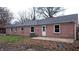 Exterior rear of the home showing pink brick, white trim, a small patio, and a well-manicured lawn at 3121 W 13Th St, Anderson, IN 46011