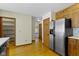 Well-lit kitchen with stainless steel refrigerator and wooden cabinets with a view into the other rooms at 4859 W 150 N, Greenfield, IN 46140