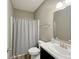 Bathroom with white sink and cabinets, shower with grey curtain and wood-look flooring at 673 Ballycastle Ct, Pendleton, IN 46064