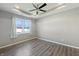 Bedroom with wood-look flooring, tray ceiling, large window, and neutral paint at 673 Ballycastle Ct, Pendleton, IN 46064