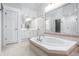 Well-lit bathroom featuring a jacuzzi bathtub, large mirrors, and neutral tile flooring, perfect for relaxation at 8845 Otter Cove Cir, Indianapolis, IN 46236