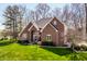 View of the home's red brick facade, large windows, manicured lawn, and walkway to the front door at 8845 Otter Cove Cir, Indianapolis, IN 46236