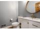 Clean half bathroom with gray walls, round mirror, and a white vanity with modern fixtures, exuding simple elegance at 8845 Otter Cove Cir, Indianapolis, IN 46236