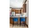 This is a closer view of a light countertop, dark cabinets and a couple of blue barstools in the kitchen at 8845 Otter Cove Cir, Indianapolis, IN 46236