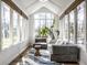 Bright sun room with many windows and hardwood floors offers a sitting area with comfortable grey furniture at 8845 Otter Cove Cir, Indianapolis, IN 46236