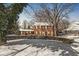 Beautiful brick two-story home featuring mature trees, manicured hedges, and a snow-covered front yard at 925 Forest Dr, Anderson, IN 46011