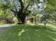 Well-manicured lawn and mature trees surround a two-story brick house with blacktop drive at 925 Forest Dr, Anderson, IN 46011