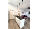 Open concept kitchen with stainless steel refrigerator, black countertop island, barstools, and open sightlines to living area at 1042 Nelson Ave, Indianapolis, IN 46203