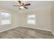 Neutral bedroom showcasing wood-look flooring, ceiling fan, and natural light from two windows at 1611 Orchard Ln, Anderson, IN 46011