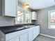 The kitchen features white cabinets, black countertops, stainless steel sink, gray walls, and new light wood flooring at 1235 Indiana Ave, Anderson, IN 46012
