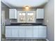 Well-lit kitchen features white cabinetry, a dark countertop, and a window overlooking the outdoors at 1235 Indiana Ave, Anderson, IN 46012