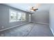 Spacious living room featuring new gray carpet, gray walls, a ceiling fan, and large window at 1235 Indiana Ave, Anderson, IN 46012