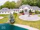 Stunning aerial view of a large white home with a circular driveway, fountain, pond, and lush landscaping at 12484 E 156Th St, Noblesville, IN 46060