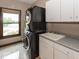 Modern laundry room with stacked washer and dryer, white cabinets, and a sink for added convenience at 12484 E 156Th St, Noblesville, IN 46060
