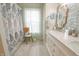 Bright bathroom featuring a single vanity with decorative mirror and a patterned shower curtain at 1501 Willshire Dr, Greenwood, IN 46143