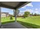View of the grassy backyard, with lush greenery and a covered patio area at 5040 Carmine St, Brownsburg, IN 46112
