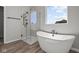 Modern bathroom features a soaking tub, a glass-enclosed shower, and a large window with natural light at 5040 Carmine St, Brownsburg, IN 46112
